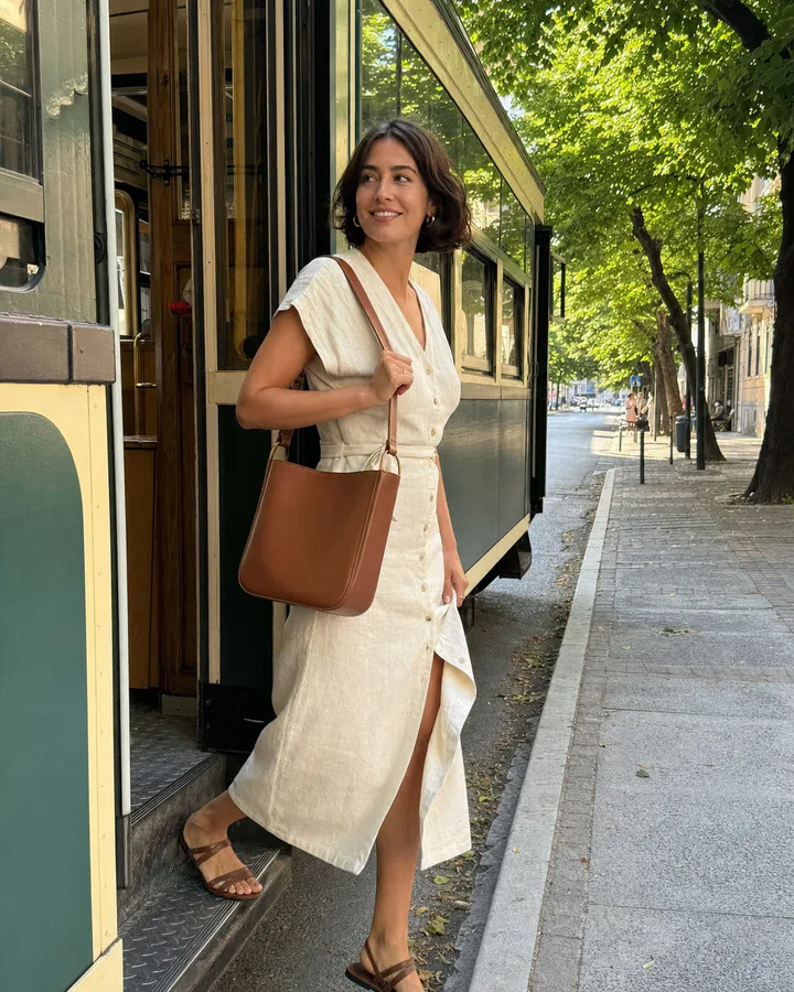 Customer carrying a cognac leather shoulder bag beside a city tram
